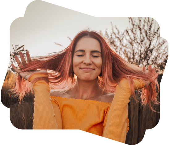 目を閉じてステキに微笑むオレンジ色の服を着た赤い髪の女の子